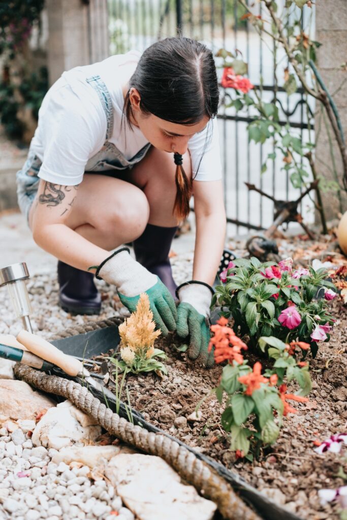 A homeowner planting flowers as part of DIY landscaping services.